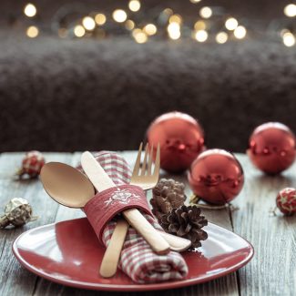 Close up of Christmas festive table setting on blurred dark background with bokeh, copy space.